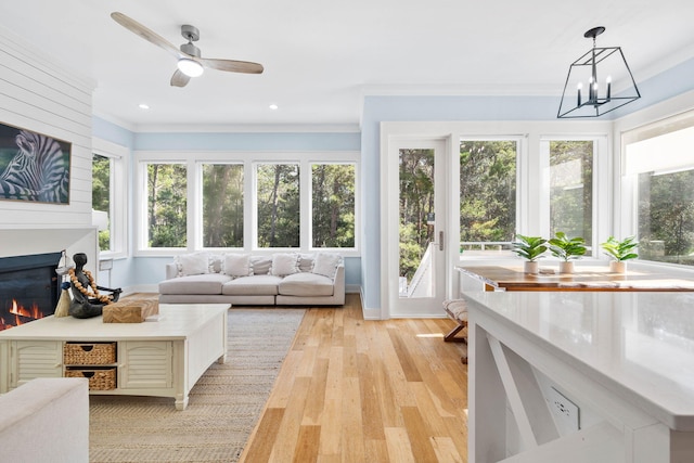 sunroom featuring ceiling fan with notable chandelier and a wealth of natural light