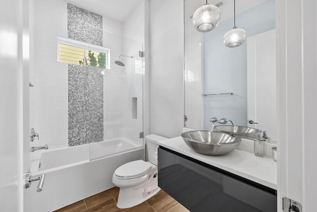 full bathroom with wood-type flooring, tiled shower / bath combo, vanity, and toilet