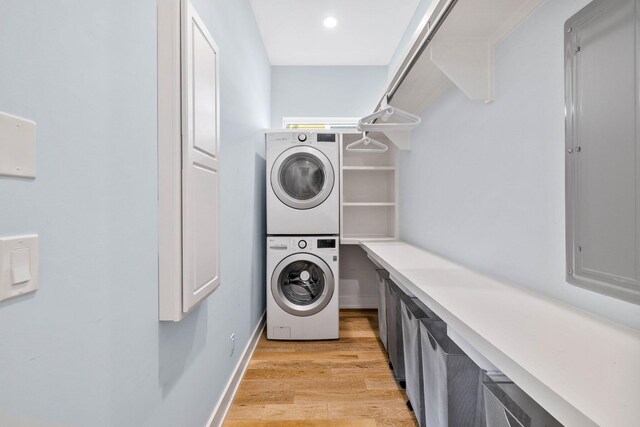 washroom with stacked washer and clothes dryer and light wood-type flooring