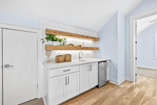 interior space featuring light wood-type flooring, sink, white cabinets, lofted ceiling, and stainless steel refrigerator