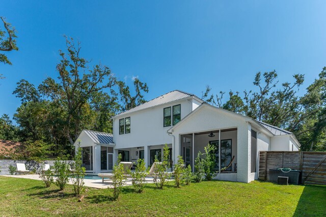 rear view of property featuring a lawn, a fenced in pool, ceiling fan, and central AC unit