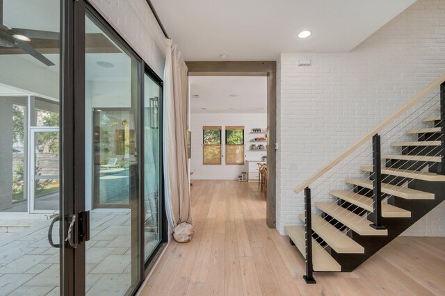 hall featuring brick wall and light wood-type flooring