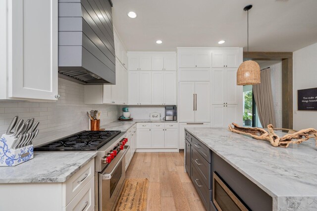 kitchen featuring pendant lighting, white cabinetry, custom range hood, and high end stainless steel range