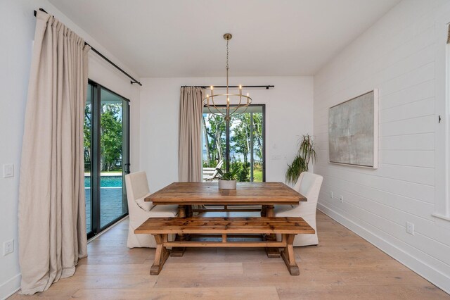 dining area with a notable chandelier, light wood-type flooring, and plenty of natural light