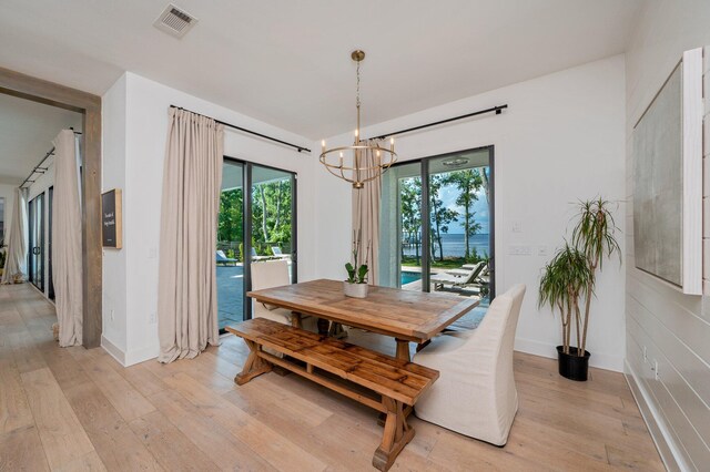 dining space with light hardwood / wood-style flooring and a notable chandelier