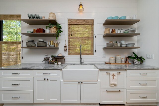 bar featuring white cabinets, light stone counters, and sink