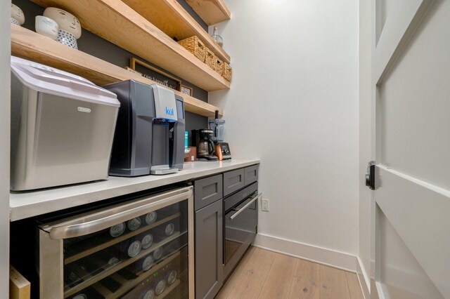 bar featuring light hardwood / wood-style flooring, beverage cooler, and gray cabinetry