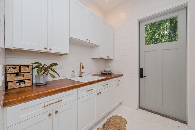 kitchen featuring butcher block countertops, white cabinets, and sink