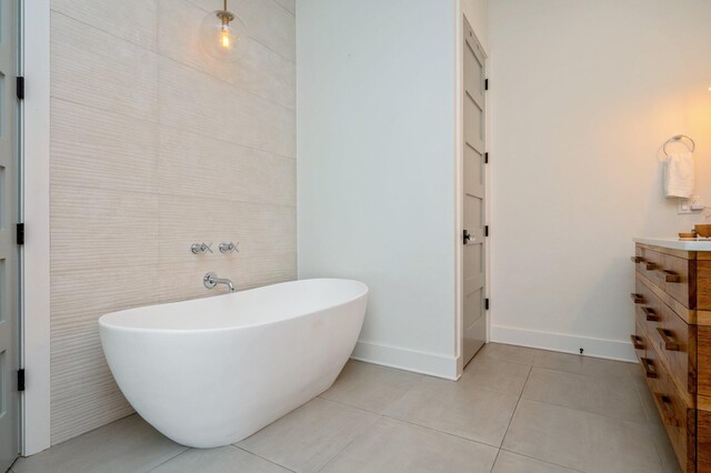 bathroom with a bathtub, tile walls, tile patterned flooring, and vanity