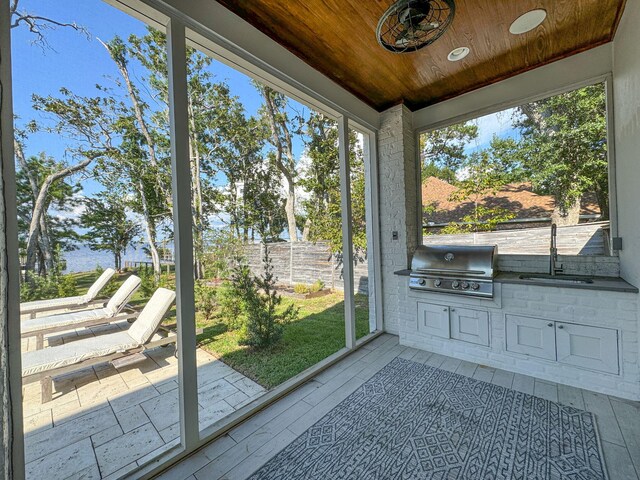 unfurnished sunroom featuring sink, a healthy amount of sunlight, and wooden ceiling