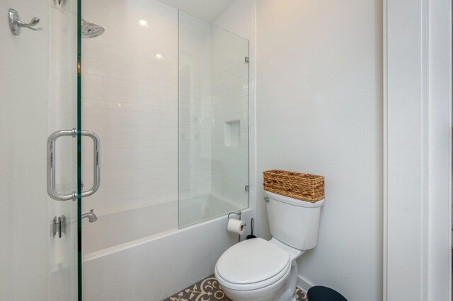 bathroom with combined bath / shower with glass door and toilet