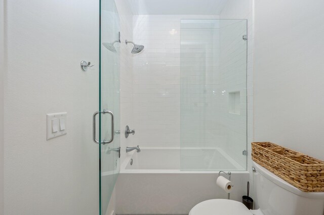 bathroom with enclosed tub / shower combo and toilet