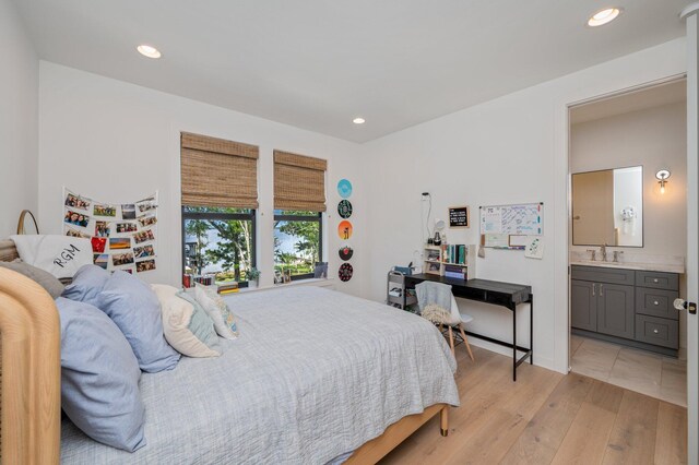 bedroom featuring light wood-type flooring, sink, and ensuite bathroom