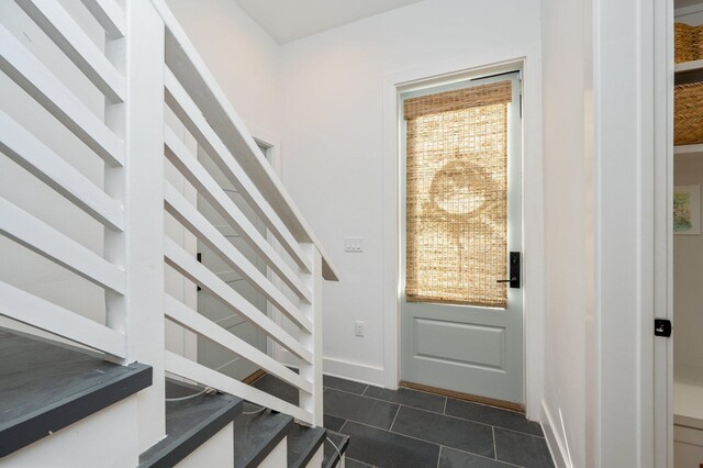 entryway with dark tile patterned flooring and a healthy amount of sunlight