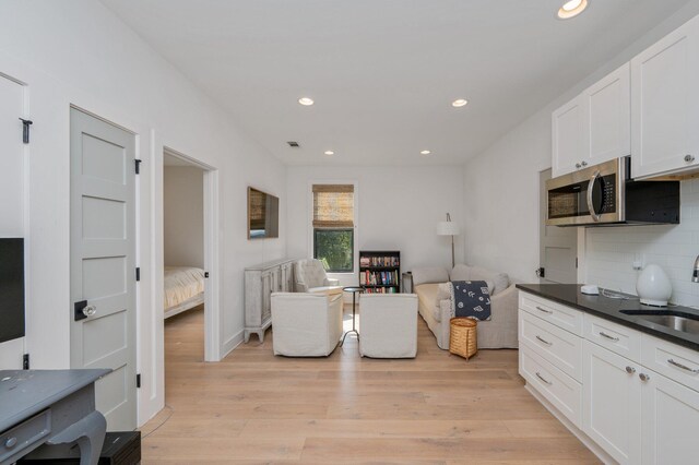 kitchen with light hardwood / wood-style flooring, sink, tasteful backsplash, and white cabinetry