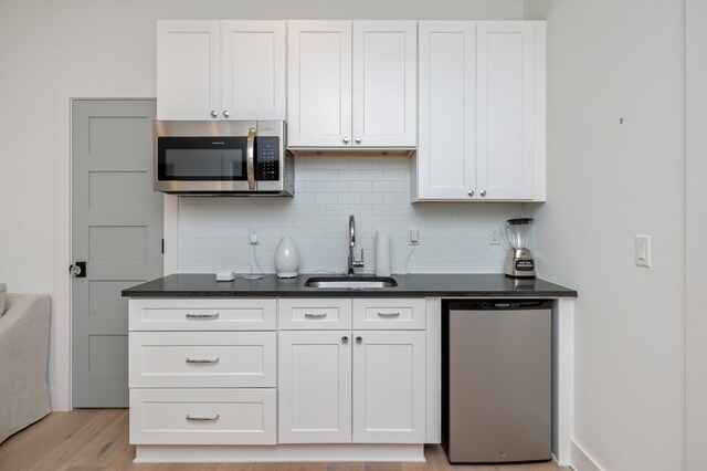 kitchen featuring appliances with stainless steel finishes, sink, light hardwood / wood-style flooring, and white cabinets