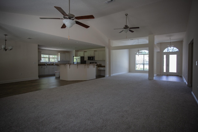 unfurnished living room featuring french doors, high vaulted ceiling, a wealth of natural light, and dark hardwood / wood-style floors