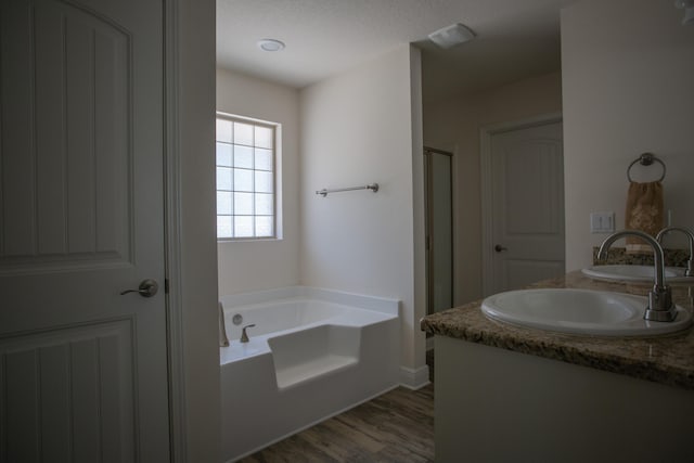 bathroom with hardwood / wood-style floors, vanity, and separate shower and tub