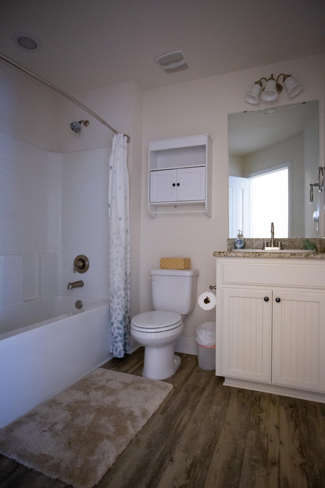 full bathroom featuring hardwood / wood-style flooring, vanity, shower / bath combo, and toilet