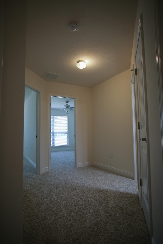 corridor featuring carpet flooring and a textured ceiling