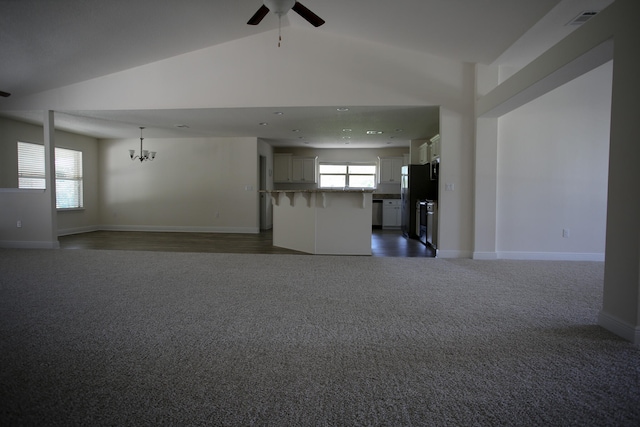 interior space with ceiling fan with notable chandelier, high vaulted ceiling, and dark carpet