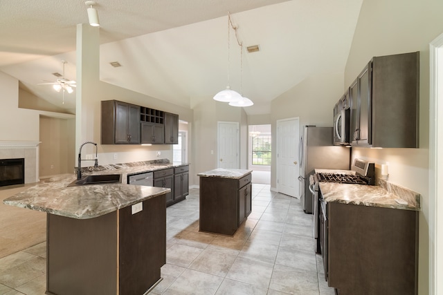 kitchen with stainless steel appliances, sink, ceiling fan, a kitchen island, and pendant lighting