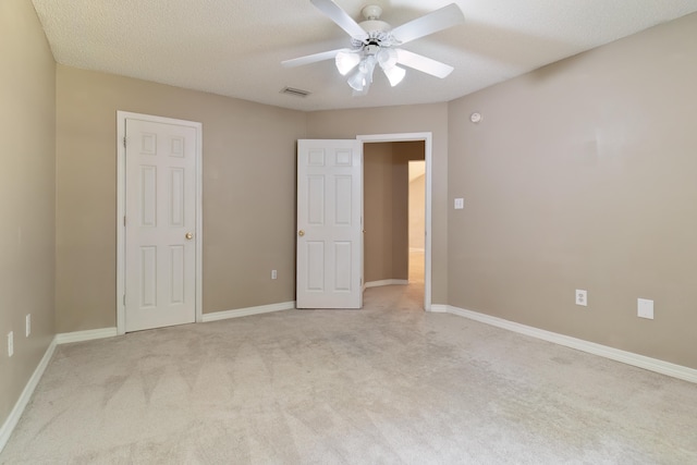 unfurnished bedroom featuring a textured ceiling, light carpet, and ceiling fan