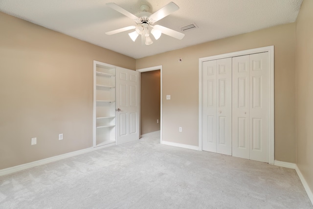 unfurnished bedroom with a textured ceiling, light colored carpet, and ceiling fan