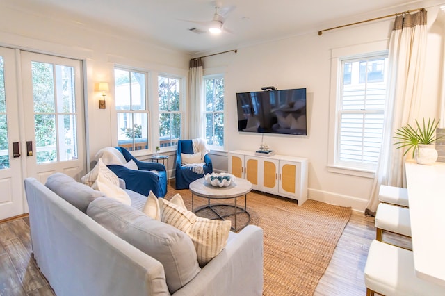 living room with a wealth of natural light, wood-type flooring, and ceiling fan