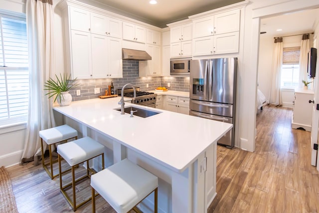 kitchen with a breakfast bar, kitchen peninsula, stainless steel appliances, and white cabinets