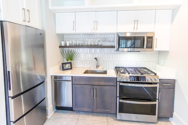 kitchen featuring decorative backsplash, white cabinetry, appliances with stainless steel finishes, and sink