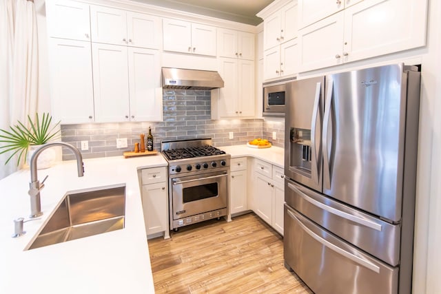 kitchen with range hood, white cabinets, appliances with stainless steel finishes, and sink