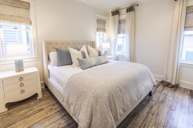 bedroom with multiple windows and dark hardwood / wood-style flooring