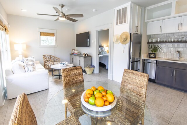 tiled dining room featuring ceiling fan and sink