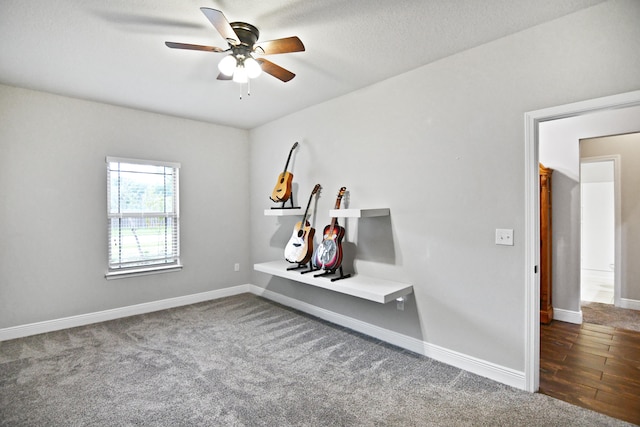 empty room featuring dark colored carpet, ceiling fan, and a textured ceiling