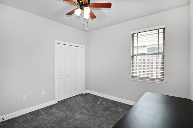 unfurnished bedroom with ceiling fan, a closet, and dark carpet