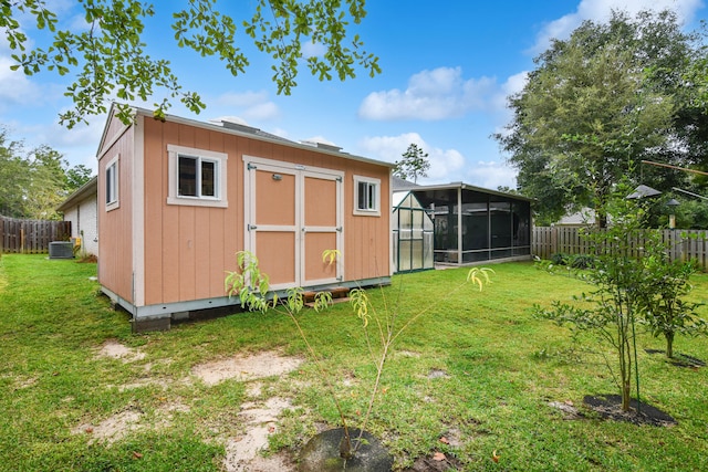 exterior space with central AC unit, a sunroom, and a storage unit