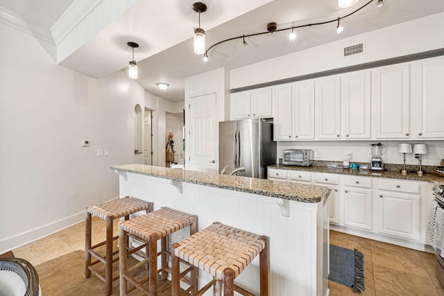 kitchen featuring white cabinets, a kitchen island, stainless steel appliances, and decorative light fixtures