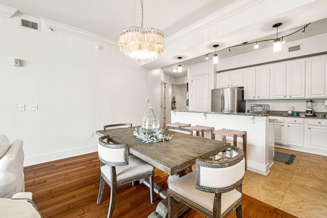 dining area featuring ornamental molding, a notable chandelier, and light hardwood / wood-style floors