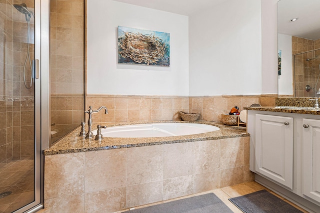 bathroom with independent shower and bath, vanity, tile walls, and tile patterned flooring