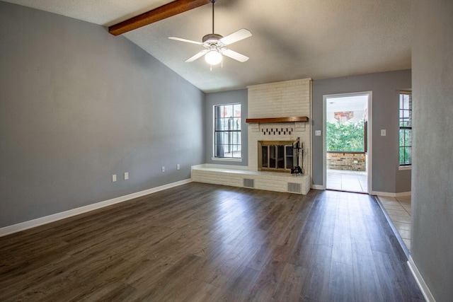 unfurnished living room with vaulted ceiling with beams, a wealth of natural light, dark hardwood / wood-style floors, and a brick fireplace