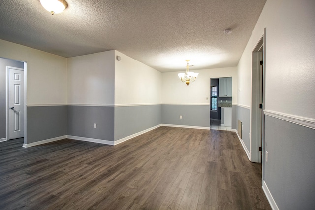 spare room with a notable chandelier, dark hardwood / wood-style floors, and a textured ceiling