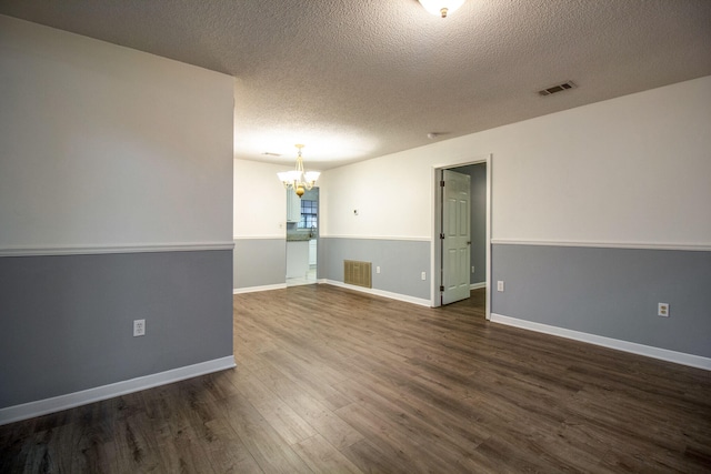 unfurnished room featuring a textured ceiling, an inviting chandelier, and dark wood-type flooring