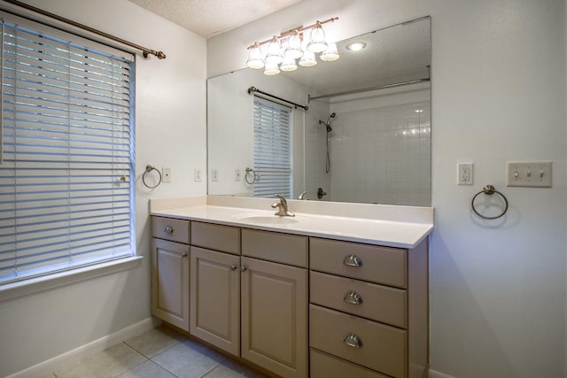 bathroom featuring tile patterned floors, tiled shower, a textured ceiling, and vanity