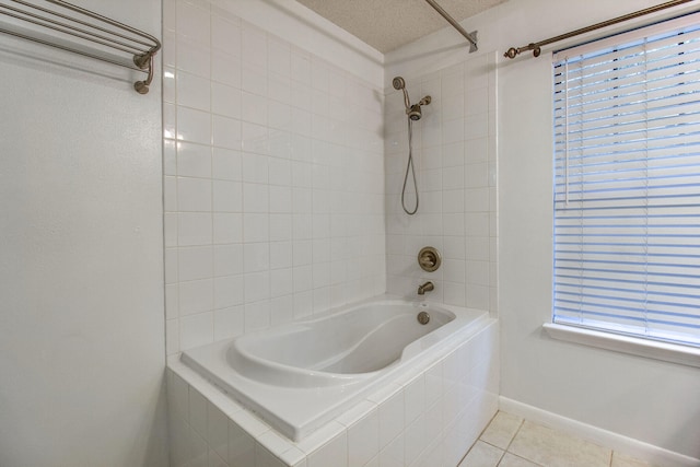 bathroom with a textured ceiling, tile patterned floors, and tiled shower / bath