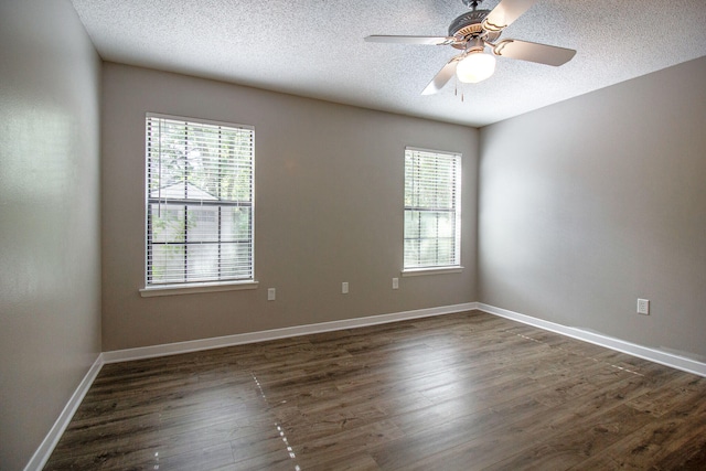 spare room with a textured ceiling, a wealth of natural light, and dark wood-type flooring