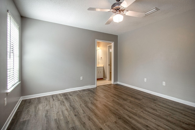 unfurnished bedroom with connected bathroom, ceiling fan, dark wood-type flooring, and a textured ceiling