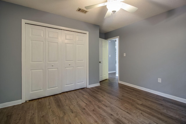 unfurnished bedroom featuring a textured ceiling, a closet, ceiling fan, and dark wood-type flooring