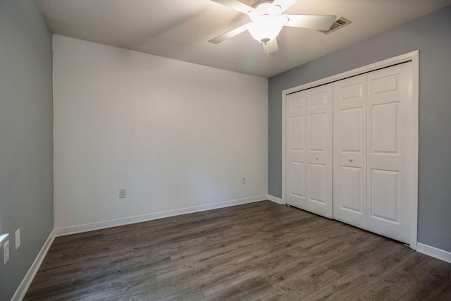 unfurnished bedroom with a textured ceiling, a closet, ceiling fan, and dark wood-type flooring