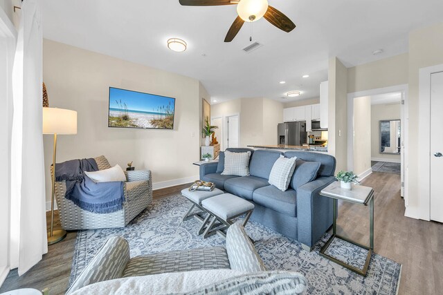 living room featuring ceiling fan and dark hardwood / wood-style flooring